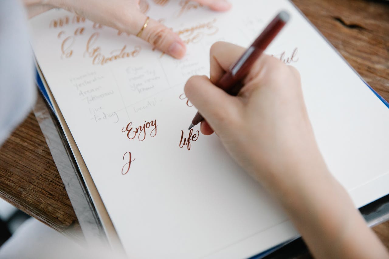 Close-up of a person practicing elegant calligraphy on paper, showcasing creativity and skill.