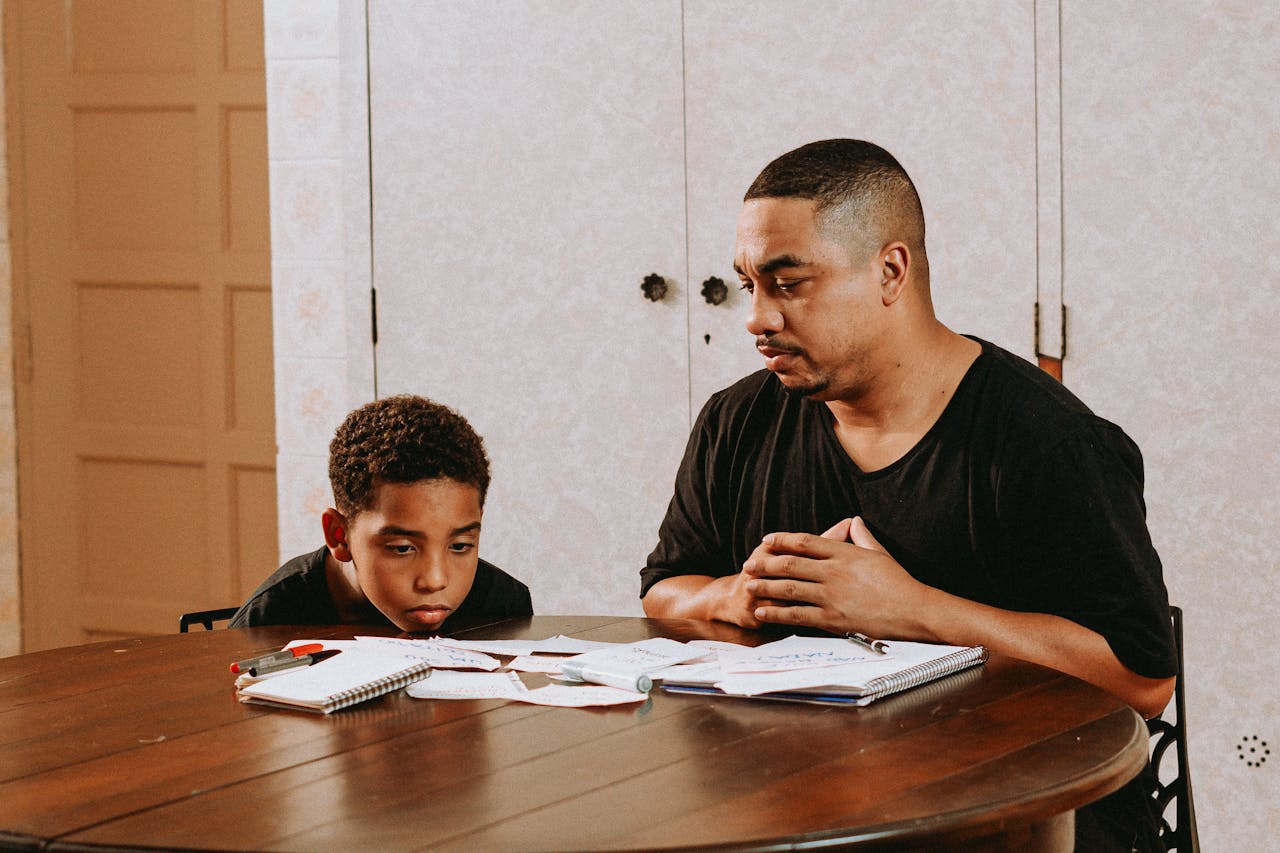 A father and son concentrate on homework and learning together indoors.